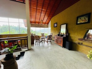 Une pièce avec un plafond en bois, un coin repas avec des chaises et une table, un bar avec un miroir, et une vue dégagée grâce à de grandes fenêtres.