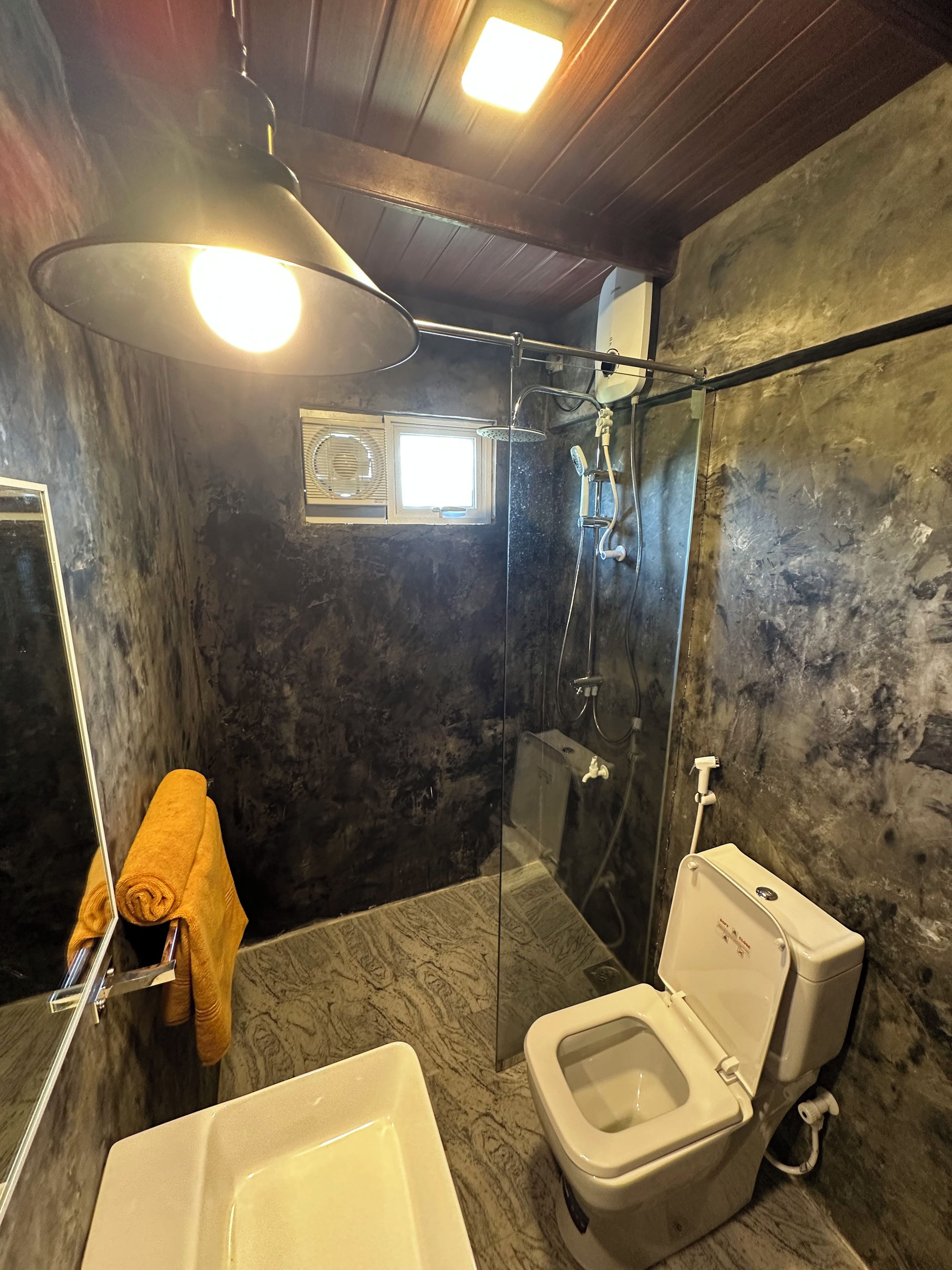 A bathroom with a glass-enclosed shower, a toilet, and a sink.