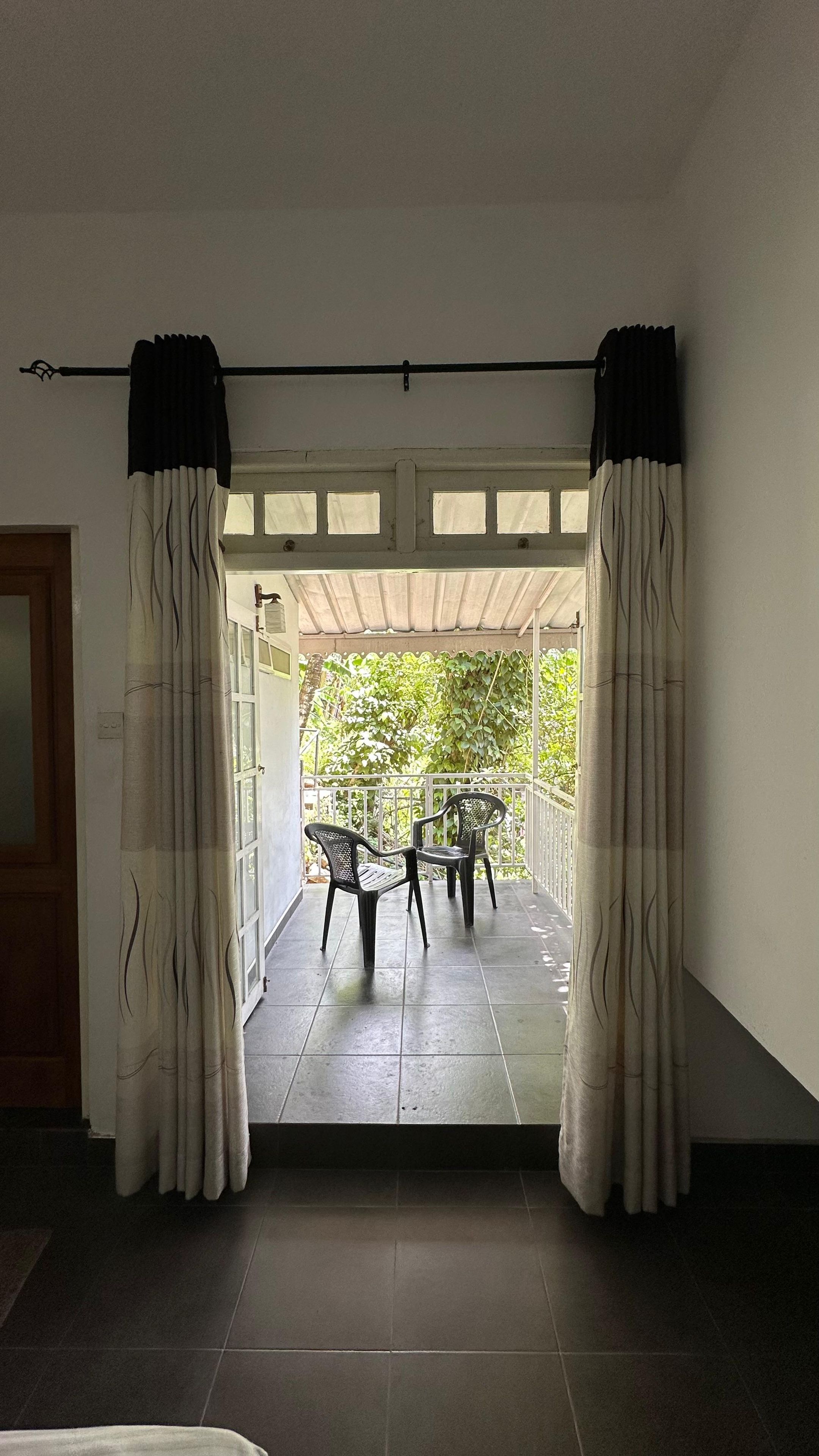 A room with a view of a covered outdoor area, featuring two chairs and a table.