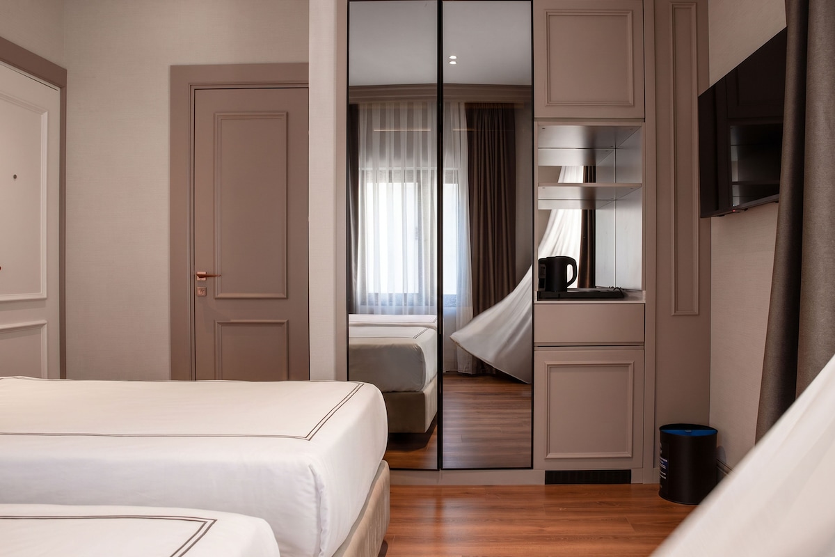 Une chambre d’hôtel équipée d’un lit, d’un miroir, d’une télévision et d’une machine à café.