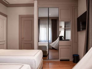 Une chambre d’hôtel équipée d’un lit, d’un miroir, d’une télévision et d’une machine à café.