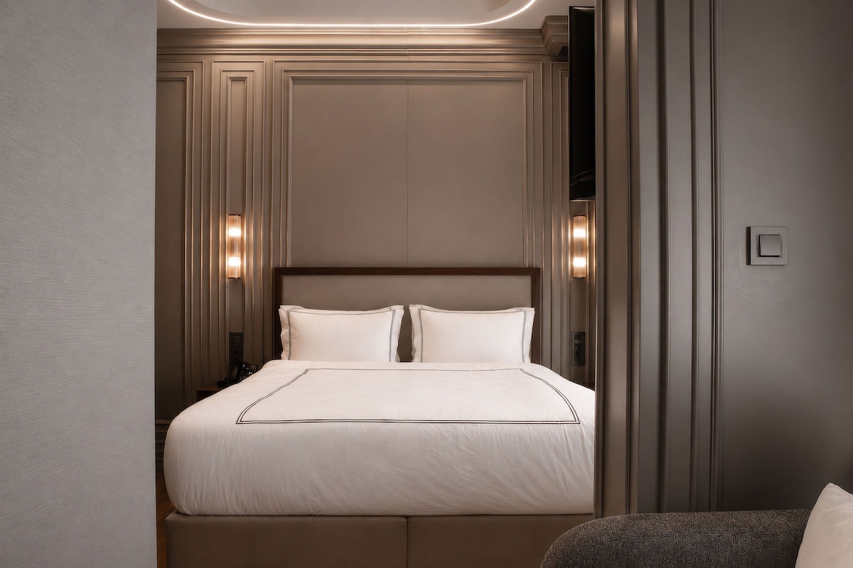 Une chambre d’hôtel avec un grand lit, une table de chevet et une chaise.