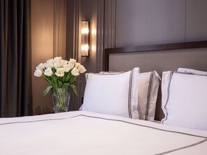 A hotel room with a bed, white pillows, a vase with white flowers, and a wall-mounted light fixture. - Soie Boutique Hotel (Istanbul)