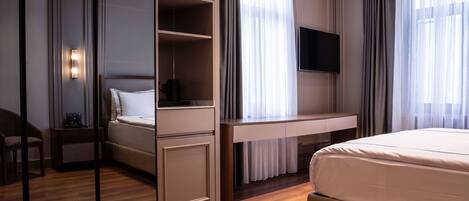 A hotel room with a bed, a desk, a chair, a television, and a mirror.