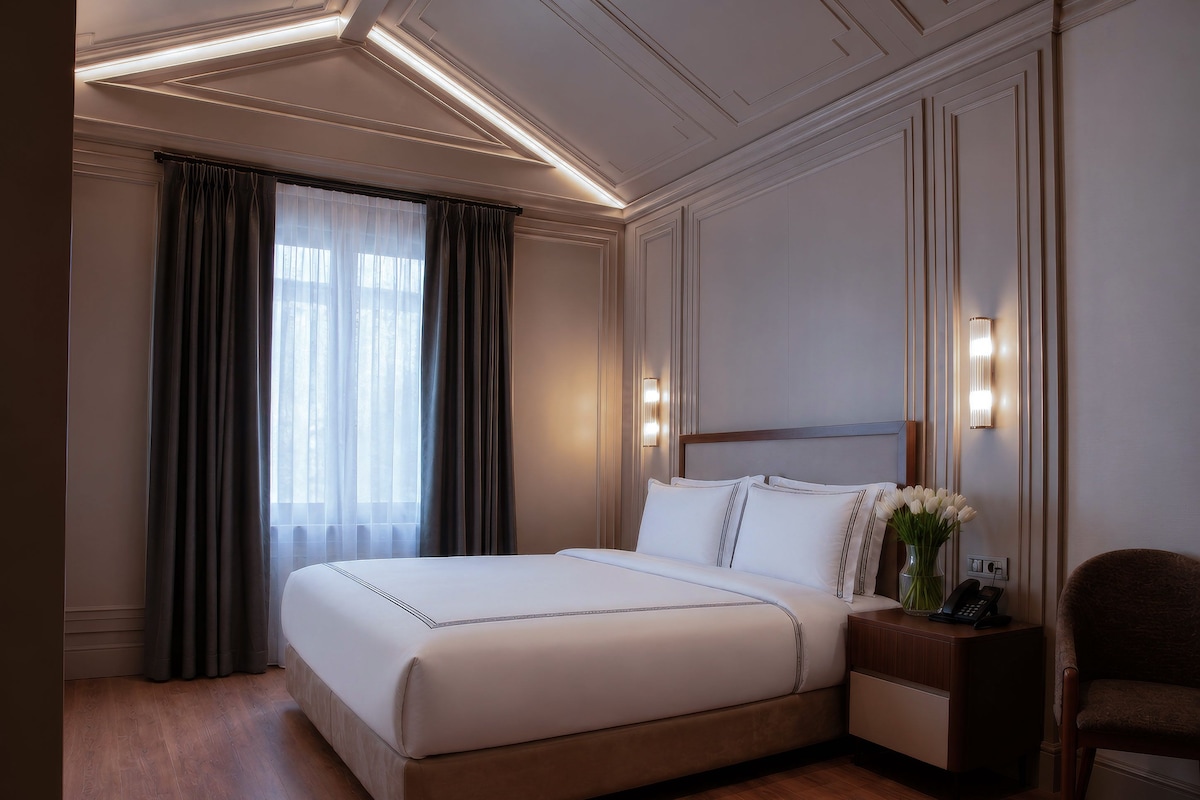Une chambre d’hôtel avec un grand lit, des lampes de chevet, une table de chevet et une chaise.
