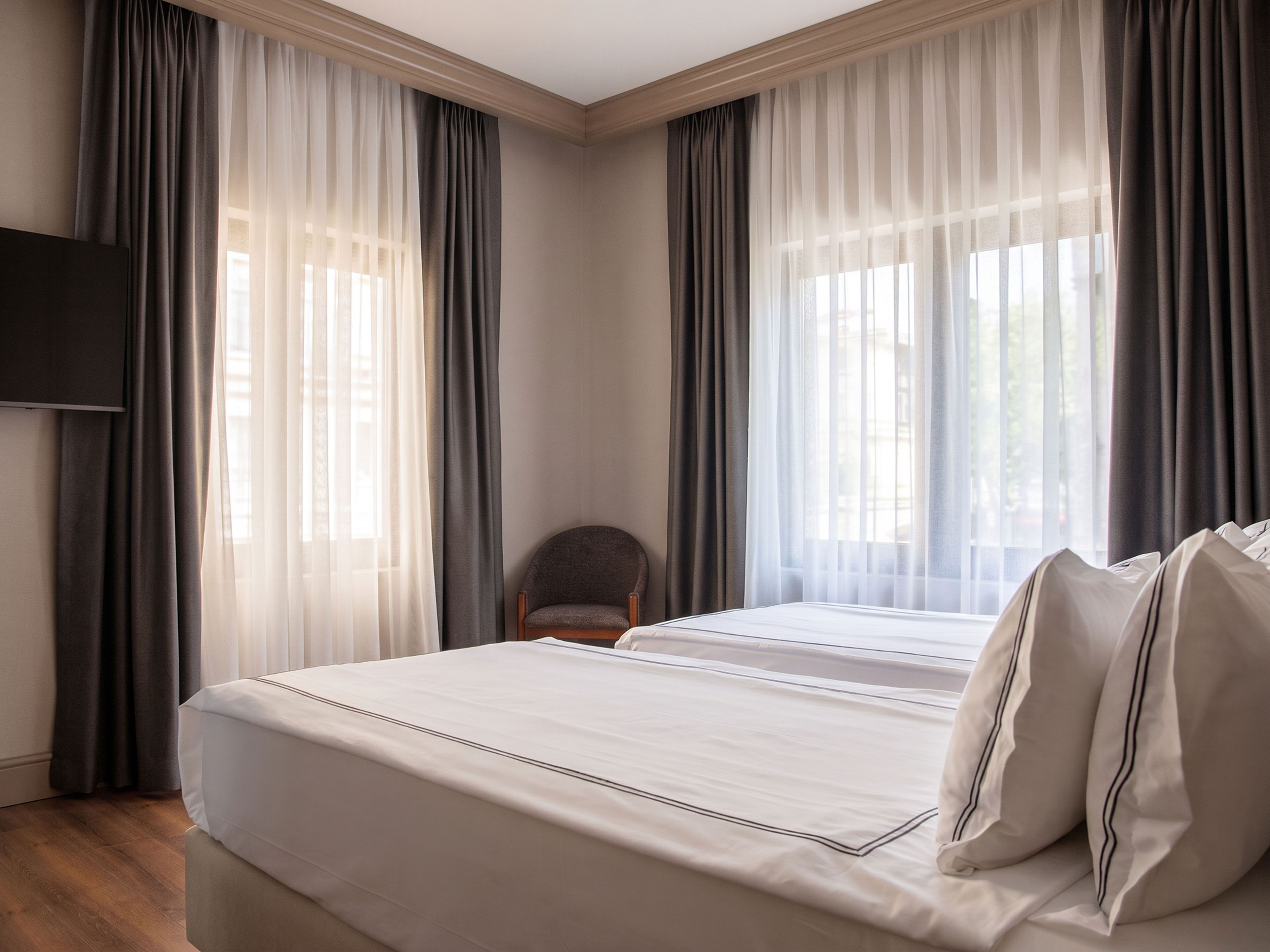 A hotel room with a large bed, a chair, and a TV.