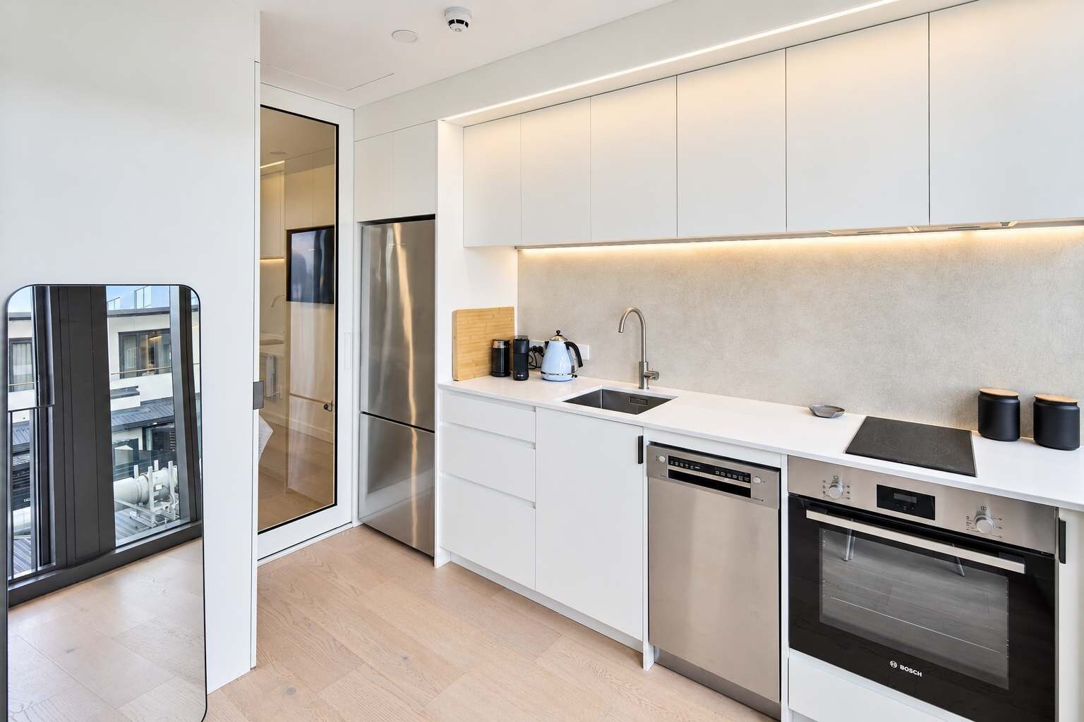 Eine moderne Küche mit weißen Schränken, Edelstahlgeräten und einem Bosch-Backofen.