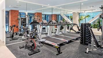 Ein modernes Fitnessstudio mit Cardiogeräten, Gewährleistungsausrüstung und einer Spiegelwand.