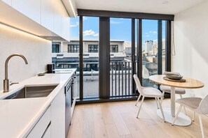 Eine moderne Küche mit einem großen Fenster, einem Essbereich mit Tisch und Stühlen und Blick auf die Stadt.