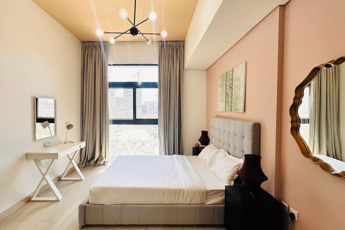 Una camera d'hotel con un letto grande, una scrivania, una sedia, uno specchio e vista sulla città.