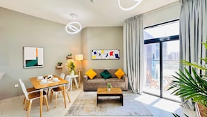 Uma sala de estar moderna com área de jantar, um sofá com almofadas, uma mesa de centro e uma grande janela com cortinas.