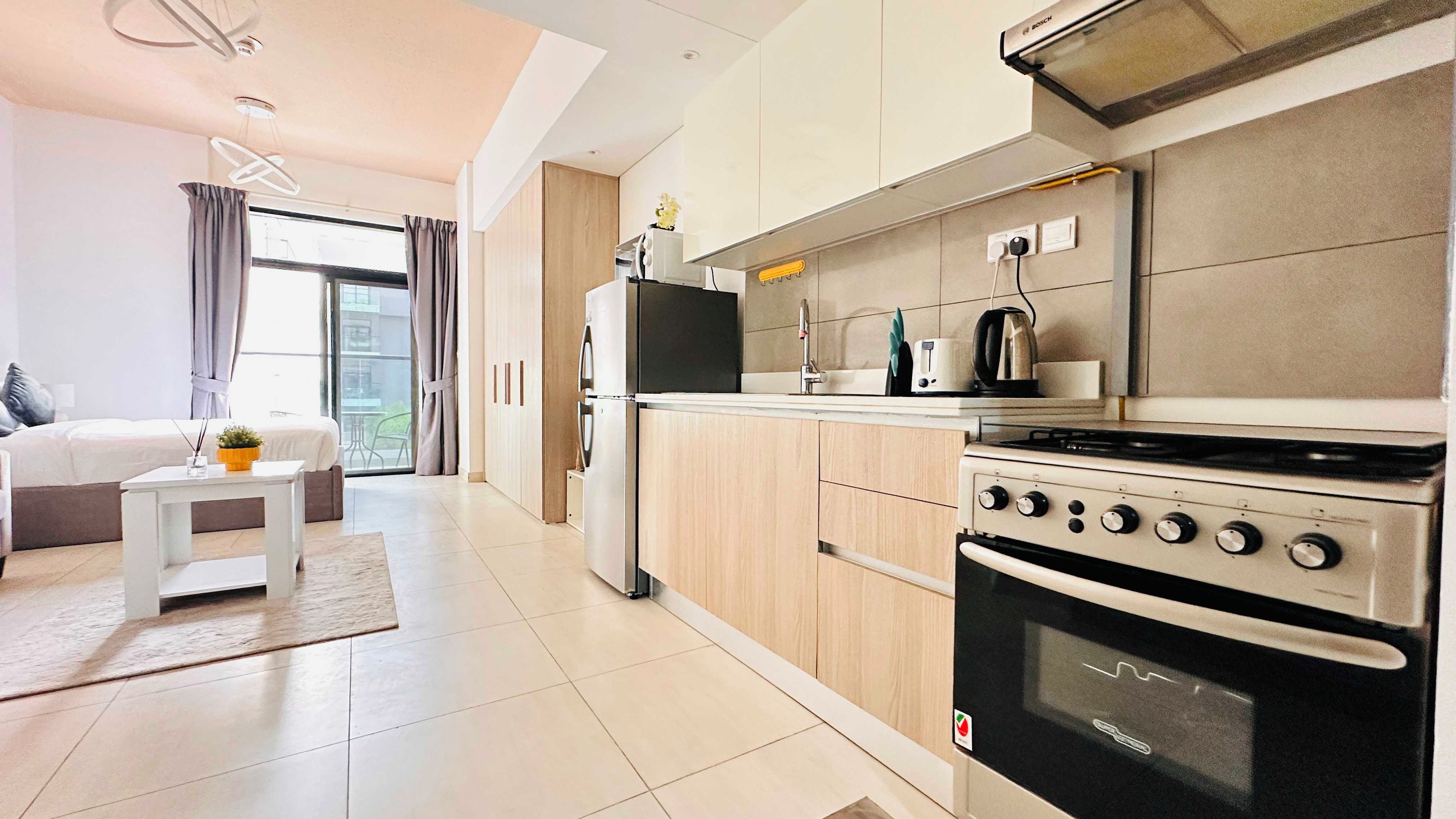 A modern kitchen with a built-in oven, a stove, and a microwave. There is a small dining table with a plant on it.