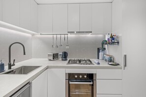 A modern kitchen with a built-in oven, a gas stove, and a sink. - High-Floor Valley Escape | Pool, Gym & Views (Brisbane)