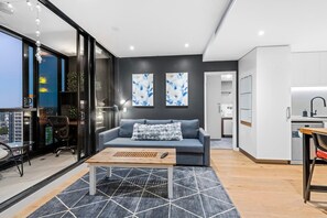 A modern living room with a sofa, coffee table, and artwork on the wall. - High-Floor Valley Escape | Pool, Gym & Views (Brisbane)