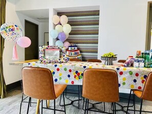 A dining area with a birthday cake, balloons, and a polka-dotted tablecloth.
