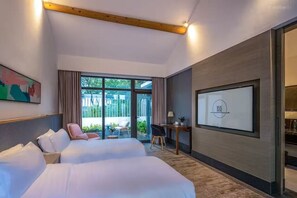 A hotel room with two beds, a desk, and a large window.