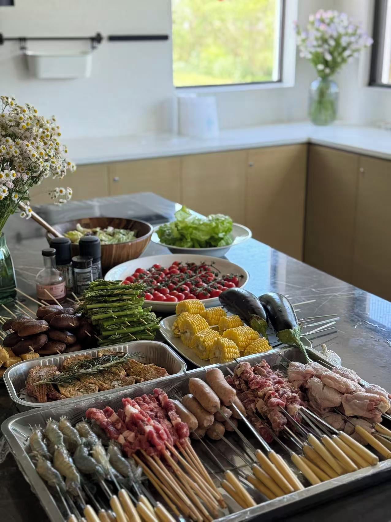A buffet table with various food items including vegetables, meats, and a flower vase.