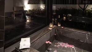 A marble-floored bathroom with a bathtub, a towel, and rose petals on the floor. - Yiyi Zhenxuan Hostel (Shanghai)