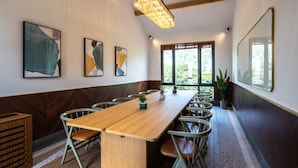 A conference room with a long wooden table, metal chairs, and abstract wall art. - Yiyi Zhenxuan Hostel (Shanghai)