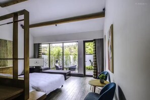 A modern hotel room with a large bed, a desk, and a view of the outdoors.