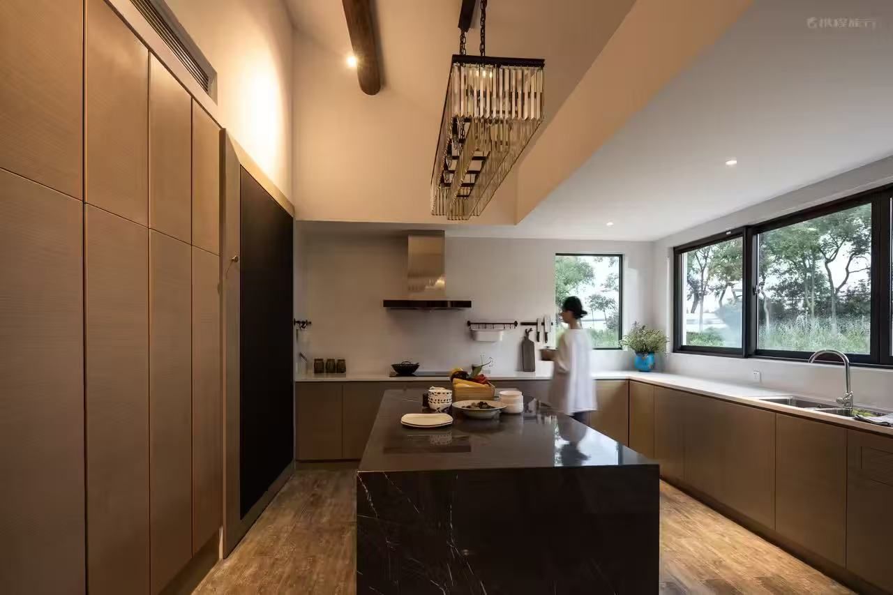 Una cocina moderna con una isla de mármol, armarios de madera y un amplio ventanal que proporciona luz natural.