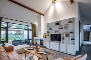 A modern living room with a fireplace, a television, and a bookshelf.
