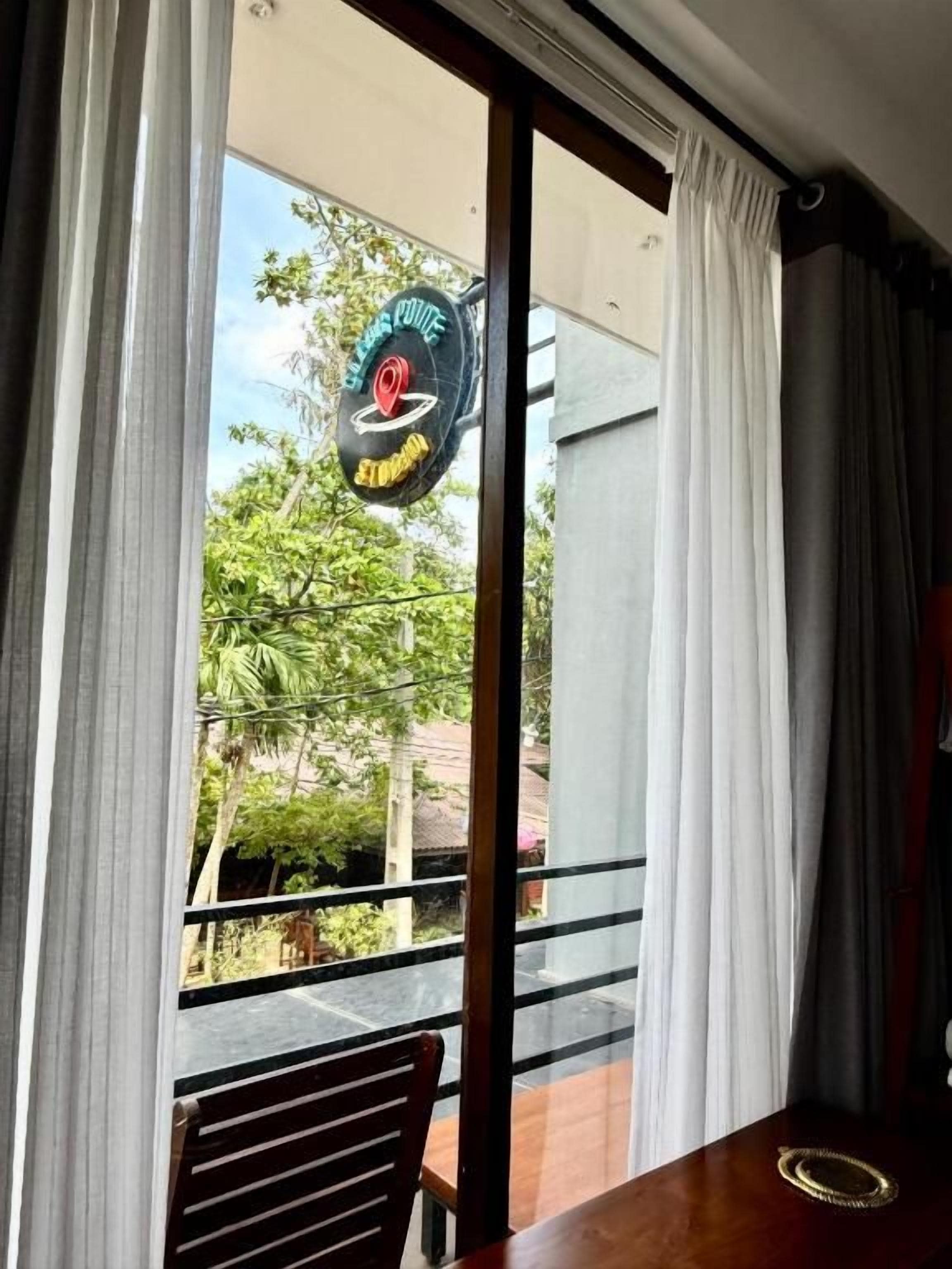 Ein Zimmer mit Blick auf ein Straßenschild, einen Balkon mit Geländer und einen Holztisch.