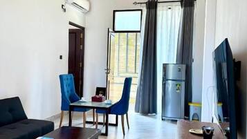 Un soggiorno moderno con soffitto in legno, una TV a schermo piatto, un divano, un tavolino da caffè e un'area pranzo con sedie e tavolo.