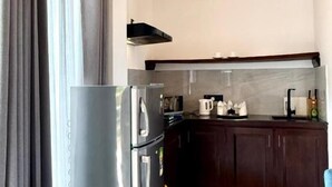 A modern kitchen with a stainless steel refrigerator, dark wooden cabinets, and a marble floor. - Clear point studio  (Dikwella)