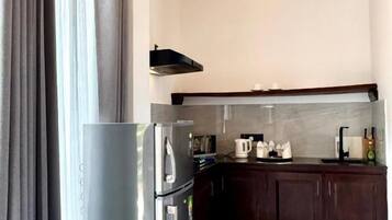 A modern kitchen with a stainless steel refrigerator, dark wooden cabinets, and a marble floor.