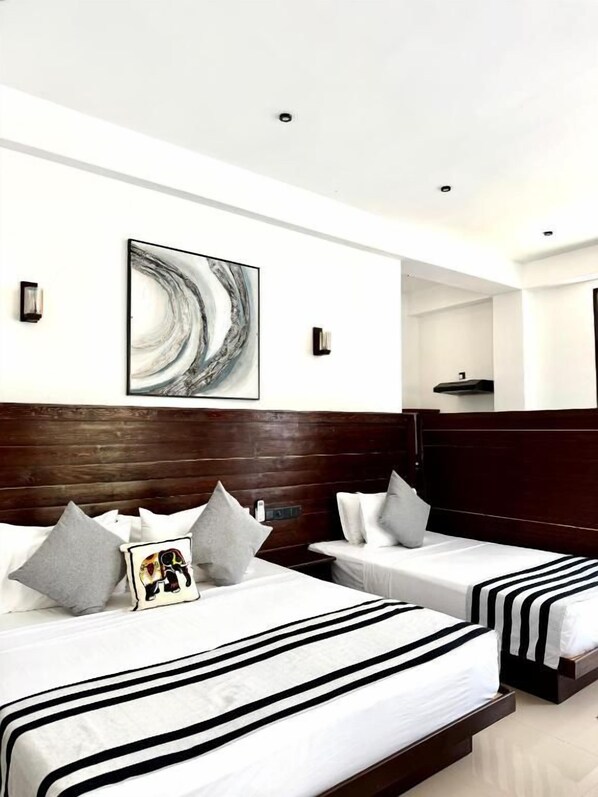 Ein Hotelzimmer mit zwei Betten, einem Holzkopfteil, einem an der Wand hängenden Kunstwerk und einem kleinen Tisch.