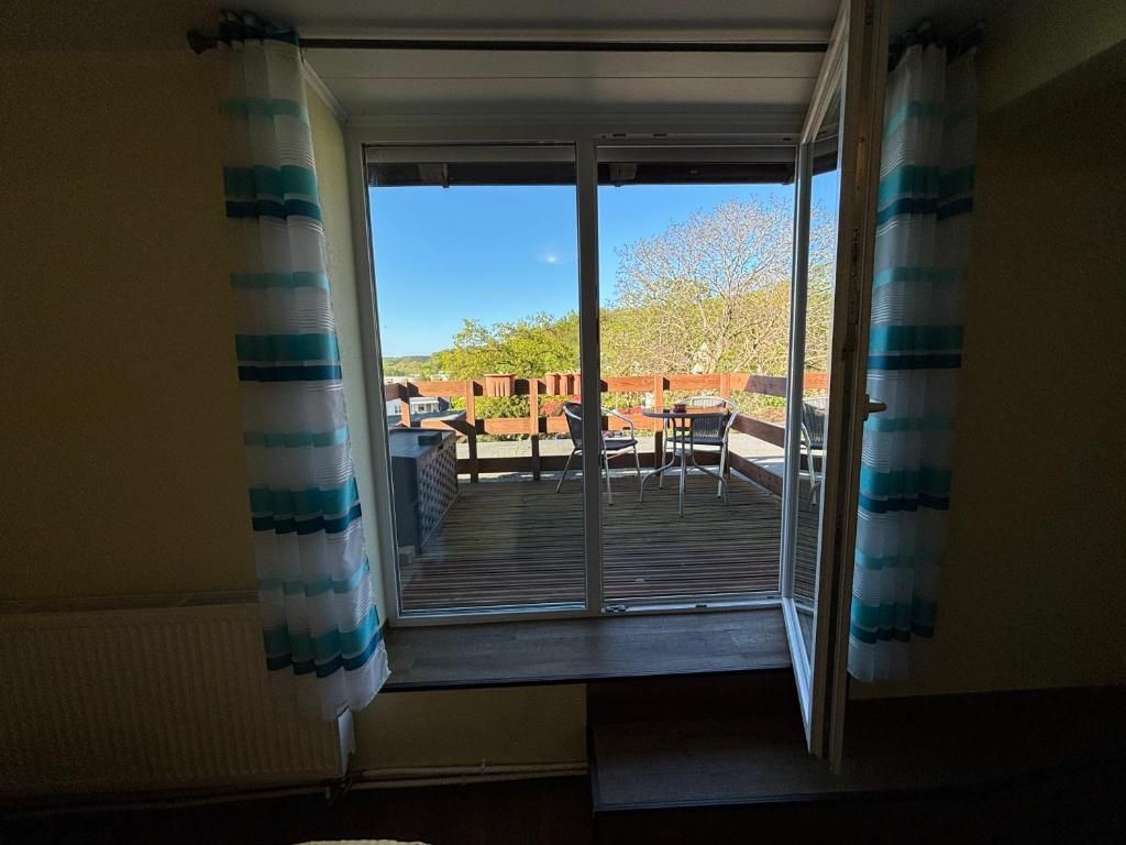 Una habitación con puerta de vidrio corrediza que da a un patio exterior con mesa y sillas.