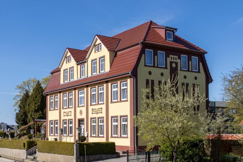A multi-story building with a symmetrical facade, large windows, and a red-tiled roof.