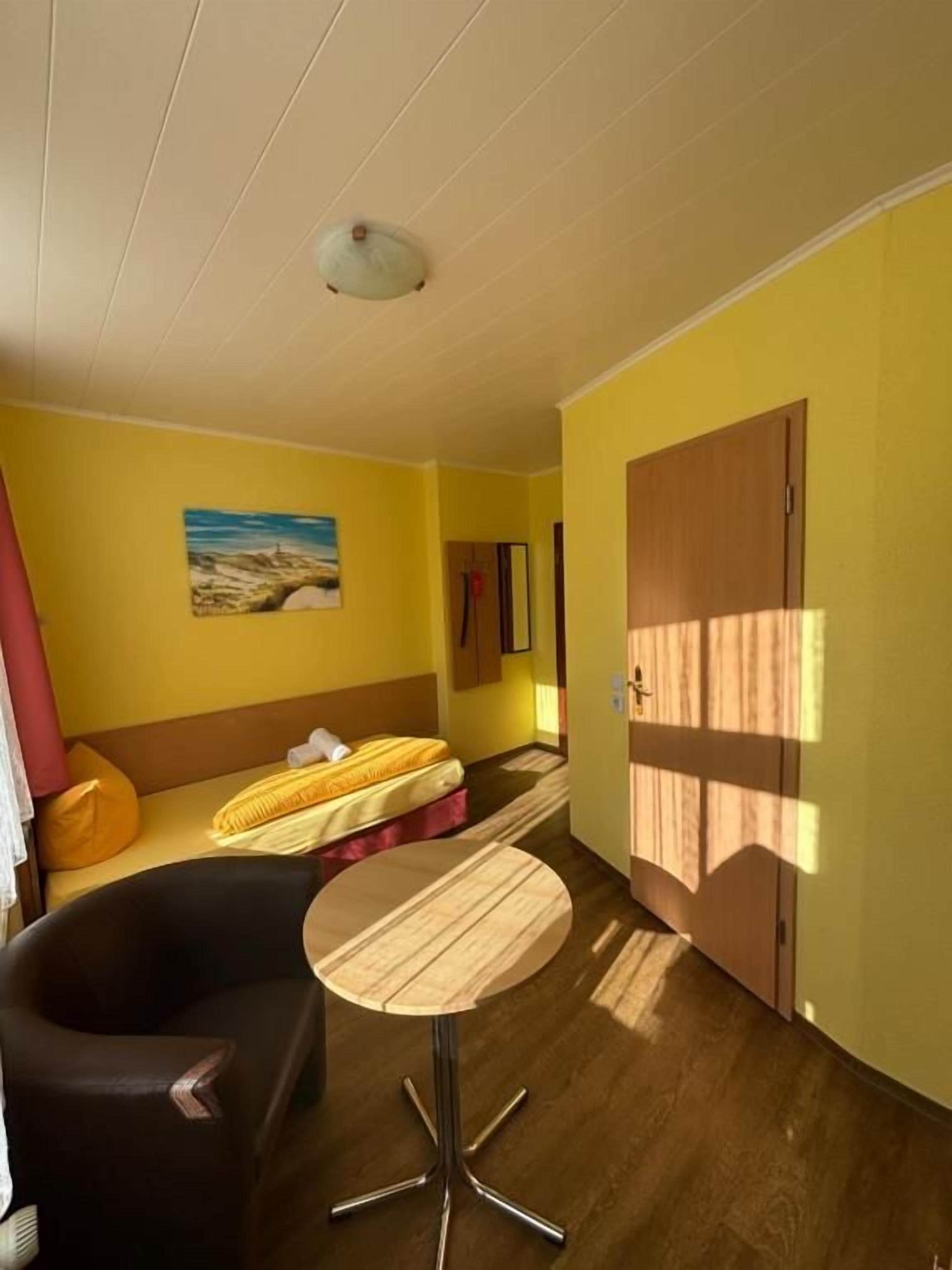 Ein Zimmer mit einem Bett, einem runden Tisch, einer Couch und einem Bild an der Wand.