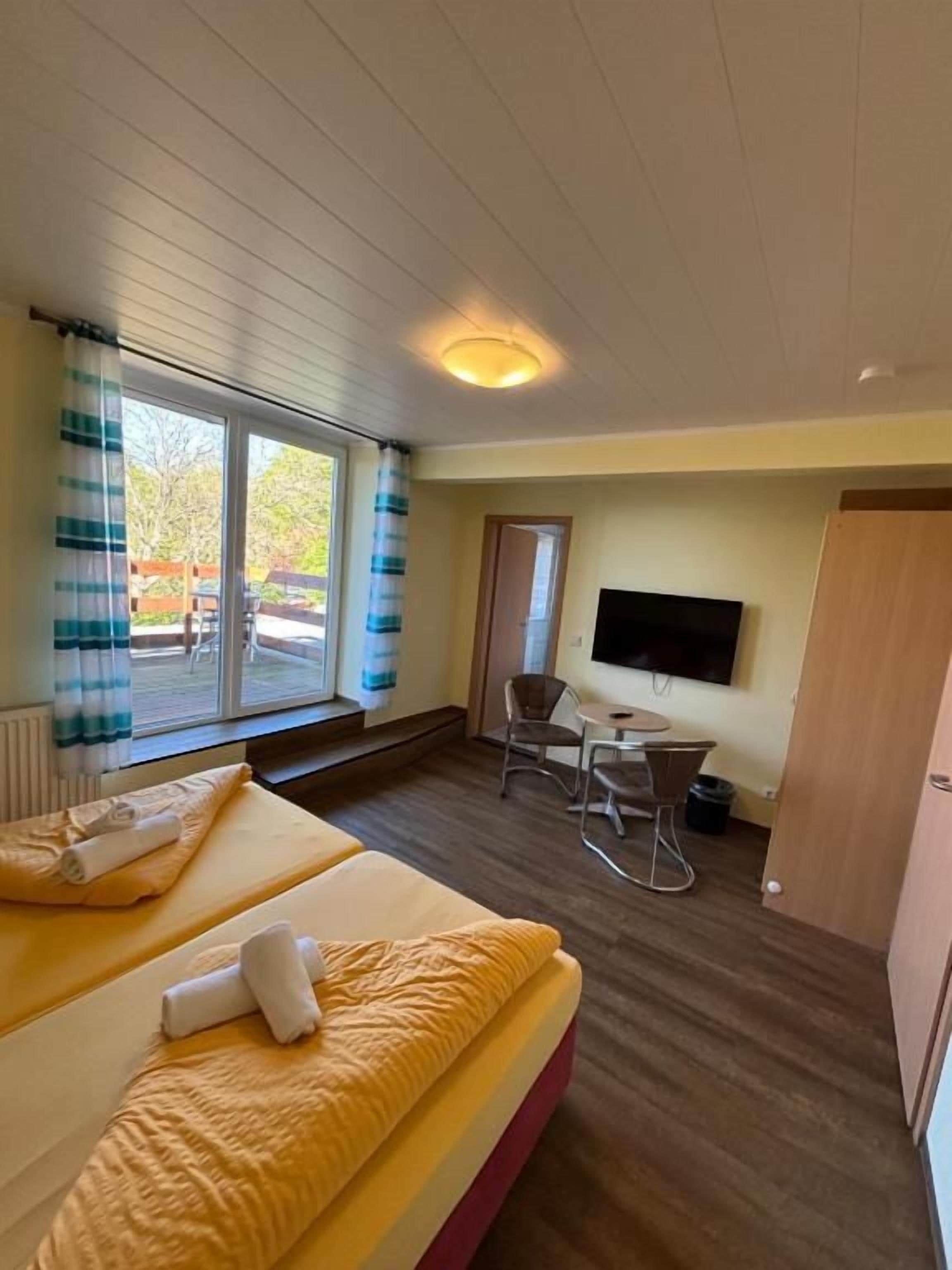 Una habitación de hotel con cama, televisor, escritorio y una silla.