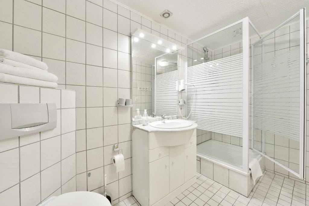 Et moderne badeværelse med toilet, håndvask og bruseniche.