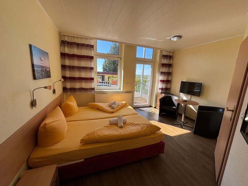 Una habitación de hotel con una cama, un escritorio, una silla, un televisor y una ventana con cortinas.