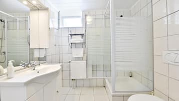 A modern bathroom with a large sink, mirror, and a walk-in shower.