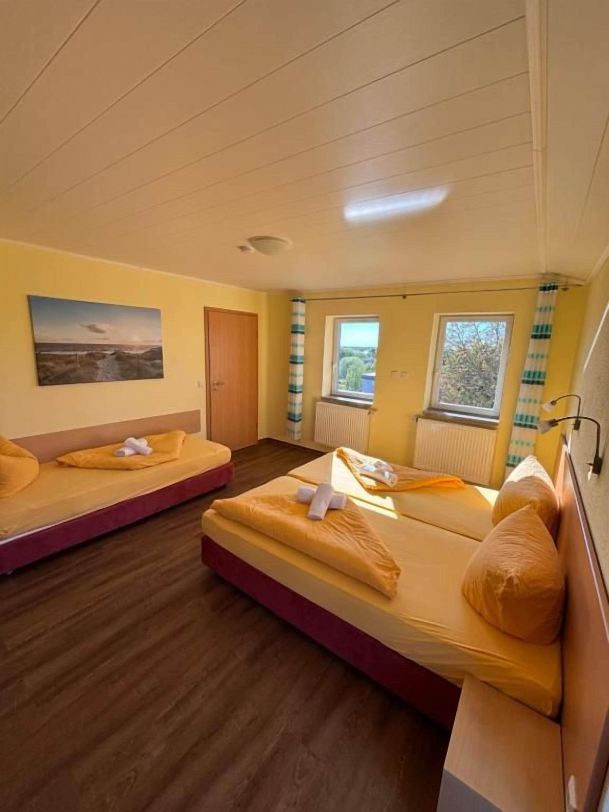 A room with two beds, a window, a radiator, and a door.