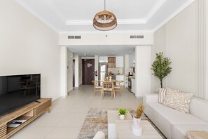 A modern living room with a flat-screen TV, wooden entertainment unit, and a dining area with a table and chairs. - Vogue | Reflection near Reem Central Park & Beach (Abu Dhabi)