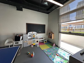 A classroom with a blackboard, play area, and window view. - Vogue | Reflection near Reem Central Park & Beach (Abu Dhabi)