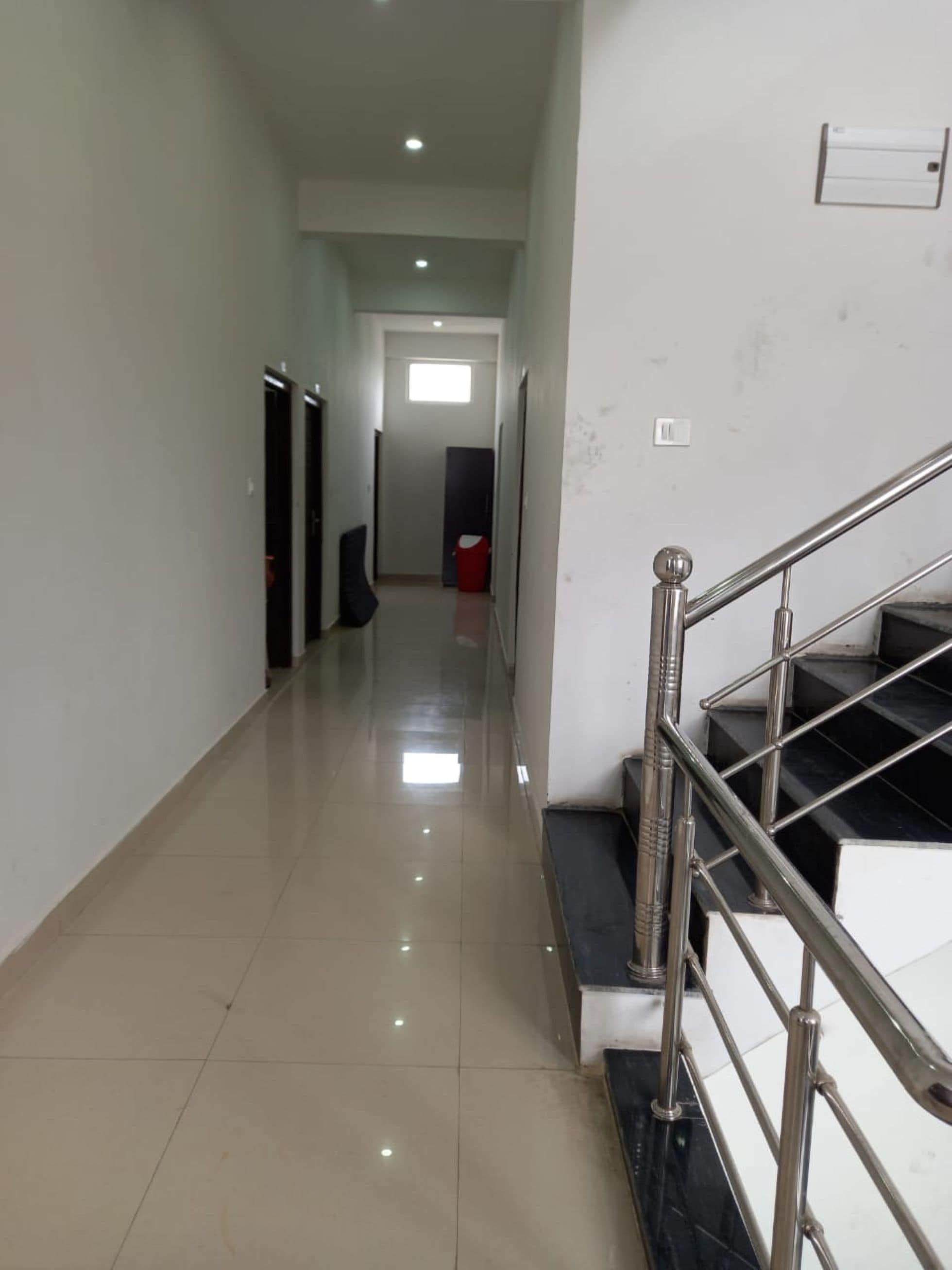 A clean, well-lit hallway with a staircase on the right, leading to a door at the end.