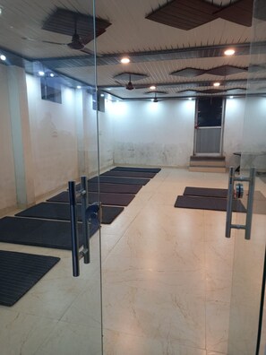 A room with a glass partition, a ceiling fan, and a door with a red handle. - Hotel Mrityunjay Coze Stay (Faizabad)