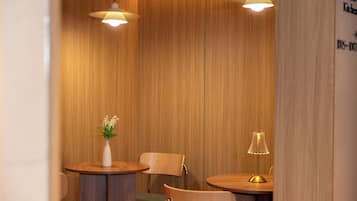 A wooden interior with two round tables, chairs, and pendant lights.