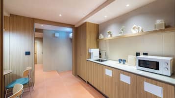 A modern kitchen with a microwave, sink, and two chairs.