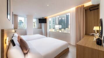 Habitación de hotel con una cama grande, un escritorio, un televisor y vistas a la ciudad.