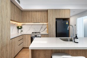 Eine moderne Küche mit Holdekor, einer Marmor-Spritzschutzwand und einem eingebauten Gasherd.
