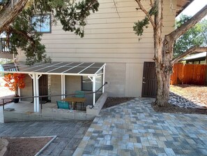 Un patio cubierto con una mesa, sillas, una planta en maceta y un árbol.