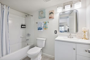 Un baño con ducha, inodoro, lavabo y espejo.