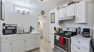 Una cocina moderna con armarios blancos, estufa de acero inoxidable y microondas.